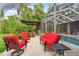 Outdoor patio with red seating, a small table, and adjacent grill area at 3204 Polo Pl, Plant City, FL 33566