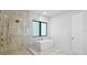Spacious bathroom with modern freestanding tub, glass shower, and large window for natural light and privacy at 2519 N Riverside Dr, Tampa, FL 33602