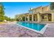 Inviting pool area with brick patio, lush landscaping, and a house in the background at 7725 Still Lakes Dr, Odessa, FL 33556