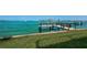 A wooden dock extends over a lush green lawn and into tranquil turquoise waters at 806 Columbus Dr, Tierra Verde, FL 33715