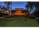Stunning home boasting a manicured lawn, brick driveway, and towering palm trees under a twilight sky at 806 Columbus Dr, Tierra Verde, FL 33715