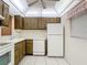 Clean kitchen featuring wood cabinets, white appliances, and tiled floors at 11485 Oakhurst Rd # 107, Largo, FL 33774