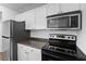 Kitchen with stainless steel refrigerator, microwave and modern black glass top stove at 2500 Winding Creek Blvd # A102, Clearwater, FL 33761