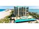 Stunning aerial view of a beachfront high-rise with a pool deck, parking, and ocean views at 1380 Gulf Blvd # 1008, Clearwater Beach, FL 33767