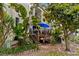 A condo with a private porch, tropical landscaping, and outdoor seating under a blue umbrella, creating a serene retreat at 240 Windward Psge # 602, Clearwater Beach, FL 33767