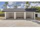 View of the detached three-car garage with open bays and concrete floors on a sunny day at 7414 Van Dyke Rd, Odessa, FL 33556