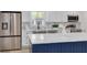 Modern kitchen boasts stainless steel appliances, marble backsplash, and a stylish navy blue island at 7414 Van Dyke Rd, Odessa, FL 33556