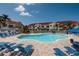 Community pool with blue lounge chairs and umbrellas, surrounded by pavers and tropical landscaping at 6011 Bahia Del Mar Blvd # 150, St Petersburg, FL 33715