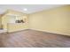 Open living room showcasing wood-look floors and kitchen access at 2619 Redford Way, Wesley Chapel, FL 33544