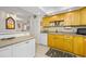Well-equipped kitchen with light wood cabinets, white appliances, and a breakfast bar at 1 Key Capri # 104E, Treasure Island, FL 33706