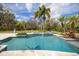 Inviting backyard featuring a sparkling pool, spa, lush landscaping, and serene surroundings at 550 E East Lake N Rd, Tarpon Springs, FL 34688