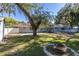 Backyard view showcasing a home with a fire pit and mature trees at 5523 Carlton Rd, New Port Richey, FL 34652
