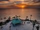 Stunning aerial view of sunset over the water, featuring a gazebo on the beach, and silhouetted palm trees at 1032 Rosetree Ln, Tarpon Springs, FL 34689
