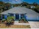 Inviting single-story home featuring a manicured lawn and tropical landscaping, enhanced by a two-car garage at 1032 Rosetree Ln, Tarpon Springs, FL 34689