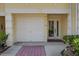 Home exterior featuring attached garage, glass front door, and brick-paved driveway at 129 Brent Cir, Oldsmar, FL 34677