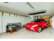 Spacious two car garage with a red convertible parked inside; includes extra storage and overhead lighting at 129 Brent Cir, Oldsmar, FL 34677