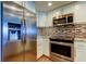 Modern kitchen features stainless steel appliances, white cabinets, and eye-catching multi-toned backsplash at 129 Brent Cir, Oldsmar, FL 34677