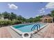 Community pool surrounded by brick pavers, lush landscaping, and plenty of lounge chairs at 129 Brent Cir, Oldsmar, FL 34677