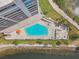 Aerial view showcasing the pool and deck with lounge chairs, tables, and umbrellas by the waterfront at 6035 Sea Ranch Dr # 505, Hudson, FL 34667