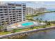 Exterior shot of a modern waterfront condo building with a pool, lounge area, and water views at 6035 Sea Ranch Dr # 505, Hudson, FL 34667