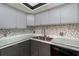 Modern kitchen with gray cabinets, glass countertops and mosaic backsplash at 1750 Harbor S Pl # 103, South Pasadena, FL 33707