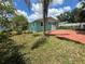 Brick patio and grassy backyard with a teal house and palm tree at 5060 86Th Ave N, Pinellas Park, FL 33782
