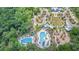 Aerial view of a community pool area with lush landscaping, clubhouse, playground, and ample parking at 16701 Vibrato Ln, Land O Lakes, FL 34638