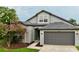 Charming single Gathering home with gray exterior, well maintained lawn, and flowering tree at 19830 Ellendale Dr, Land O Lakes, FL 34638