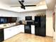 A kitchen with tiled floors and white cabinets and a black refrigerator and oven at 1109 Pinellas Bayway S # 306, Tierra Verde, FL 33715