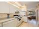 Bright kitchen features white cabinets, tile floors, and electric range at 8001 Sailboat Key S Blvd # 204, St Pete Beach, FL 33707