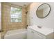 Well-lit bathroom features a shower-over-tub with tile surround, single sink vanity, and a round mirror at 49 W Boyer St, Tarpon Springs, FL 34689