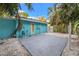 Home with turquoise exterior, concrete patio, white stone landscaping, and mature tropical trees at 6465 30Th S St, St Petersburg, FL 33712