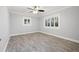 Spacious bedroom with gray wood-look floors, white trim, and a ceiling fan with light kit at 6465 30Th S St, St Petersburg, FL 33712