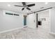 Bedroom with light grey wood-look floors, open door, sliding barn door and view to the kitchen at 6465 30Th S St, St Petersburg, FL 33712
