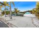Exterior view of the home featuring a long driveway, palm trees, and a white picket fence at 6465 30Th S St, St Petersburg, FL 33712