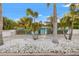 Attractive blue single-story home with a welcoming entrance, palm trees, and white stone landscaping at 6465 30Th S St, St Petersburg, FL 33712