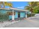 Charming blue single-story home featuring a paved entryway, white columns, and lush, tropical landscaping at 6465 30Th S St, St Petersburg, FL 33712