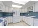 Bright kitchen with white cabinets, blue tile backsplash, and stainless steel appliances at 1 Key Capri # 102E, Treasure Island, FL 33706