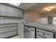 Updated kitchen with granite countertops, stainless steel appliances, and gray cabinets at 9490 Harbor Greens Way # 205, Seminole, FL 33776
