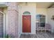 Inviting front entry with a red door and patio seating area at 1044 Blyth Hill Ct, Trinity, FL 34655