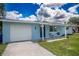 Cute blue house with white garage door and small porch at 804 St Catherine N Dr, Dunedin, FL 34698