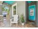 Inviting front porch featuring a teal ceiling, colorful front door, and a white chair at 131 Pennsylvania Ave, Palm Harbor, FL 34683