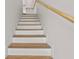 Modern staircase with hardwood steps and a white painted base, complemented by a sleek wooden handrail at 4234 4Th S St, St Petersburg, FL 33705
