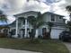 Two-story house with a green exterior, columns, and a three-car garage at 2733 Mcnair Dr, Palm Harbor, FL 34683