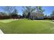 A sprawling green backyard featuring a putting green, deck with outdoor furniture, and a two-story home in the background at 4438 58Th N Ave, St Petersburg, FL 33714