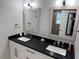Bathroom featuring double sinks with black countertops, white cabinets, and framed mirrors with modern lighting at 4438 58Th N Ave, St Petersburg, FL 33714
