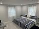 Bright bedroom featuring a neatly made bed, two windows with white curtains, and light gray walls at 4438 58Th N Ave, St Petersburg, FL 33714