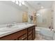 Bathroom with double vanity, large mirror, and glass-enclosed shower/tub at 9309 Rally Spring Loop, Wesley Chapel, FL 33545