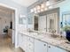 Bathroom featuring granite counters with double sinks, modern fixtures and a large decorative mirror at 11247 Corey Pavin Ln, San Antonio, FL 33576