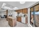 Bright kitchen featuring wood cabinetry, an island, a white dishwasher, and sliding doors to a balcony at 1651 Sand Key Estates Ct # 74, Clearwater Beach, FL 33767